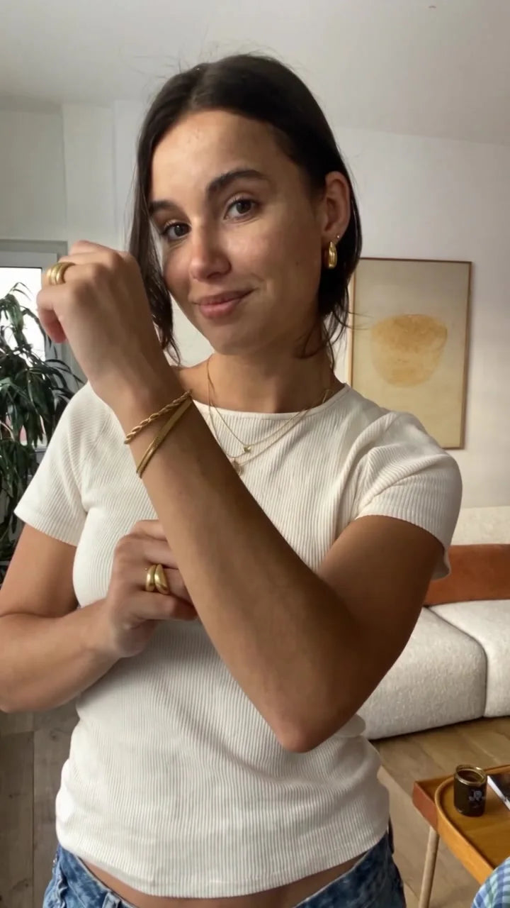 Pulsera dorada en la muñeca, con camiseta blanca en casa