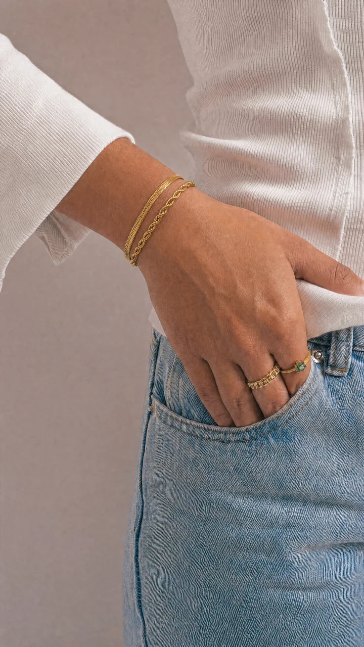 Pulsera Capas Shore y anillos dorados, mano en el bolsillo del vaquero